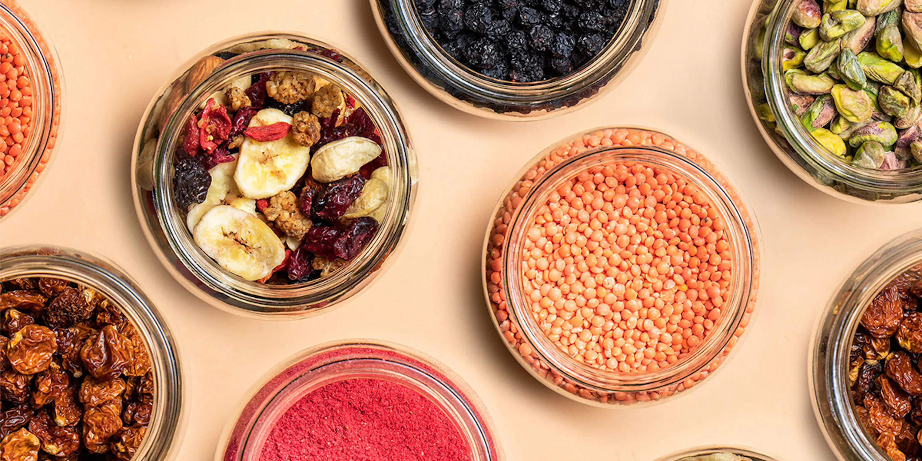a variety of dried fruits and nuts in glass jars